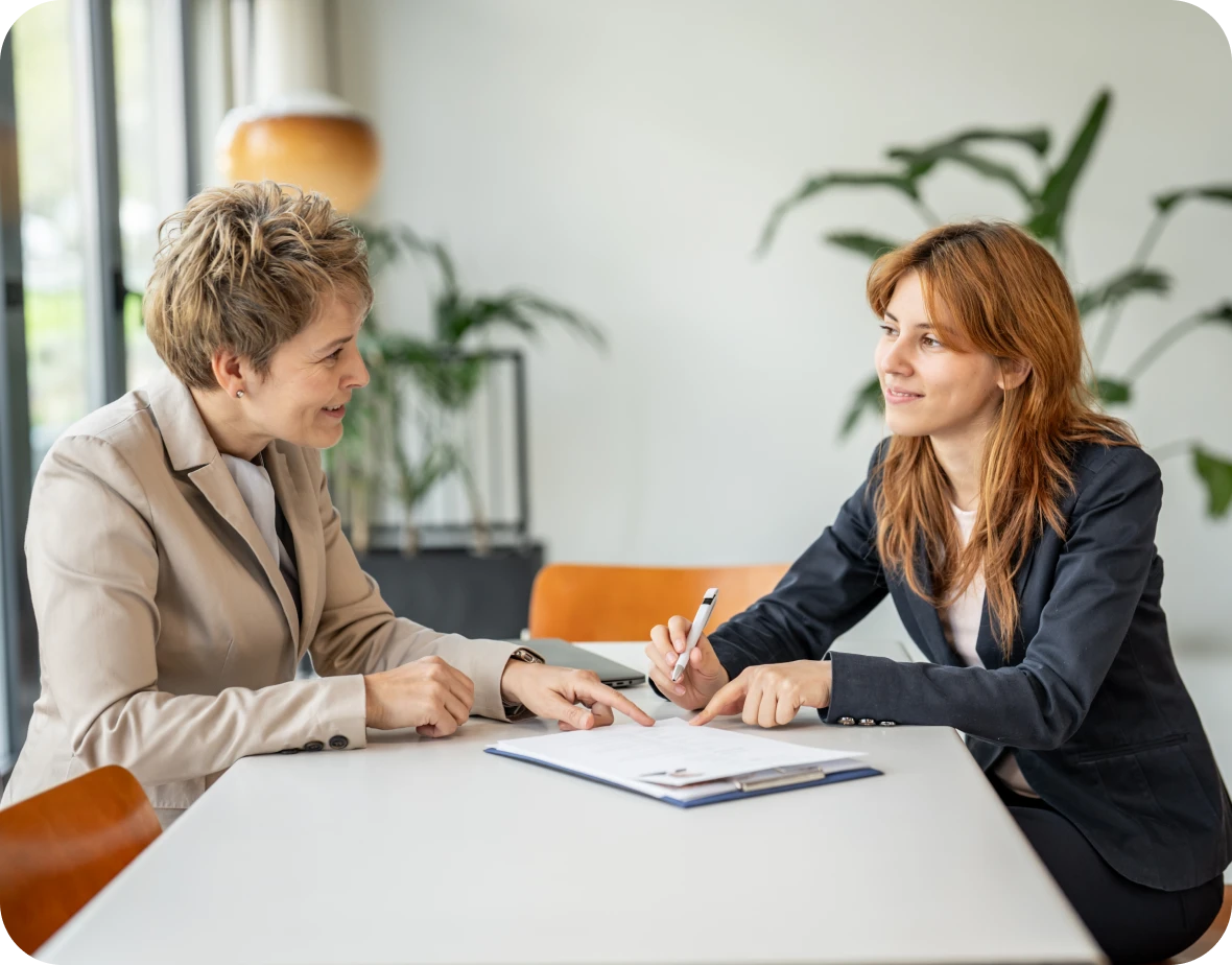 Two women discussing at a table indoors.