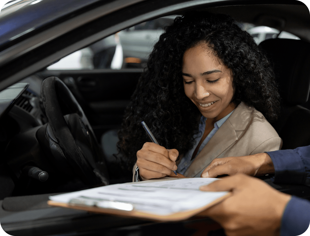 Woman signing document in a car.